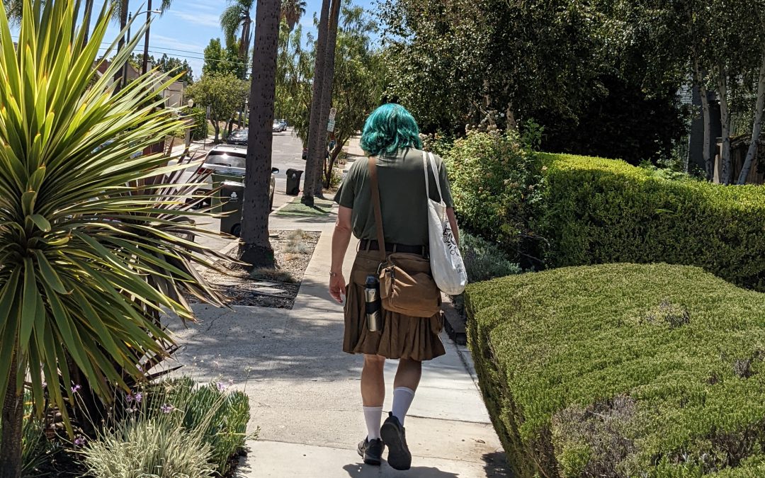 My husband walking away with teal green hair, wearing a utilikilt