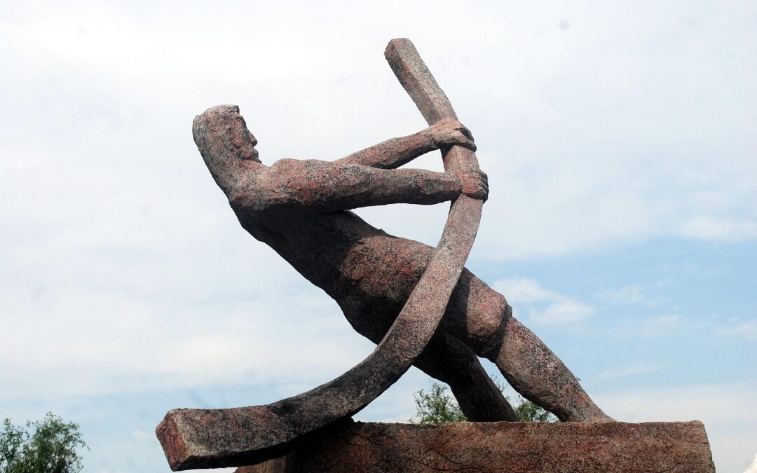Image of a large statue of a stylized human figure pulling back on a large metal bar. Photo credit https://pixabay.com/photos/artwork-statue-sculpture-expo-16923/